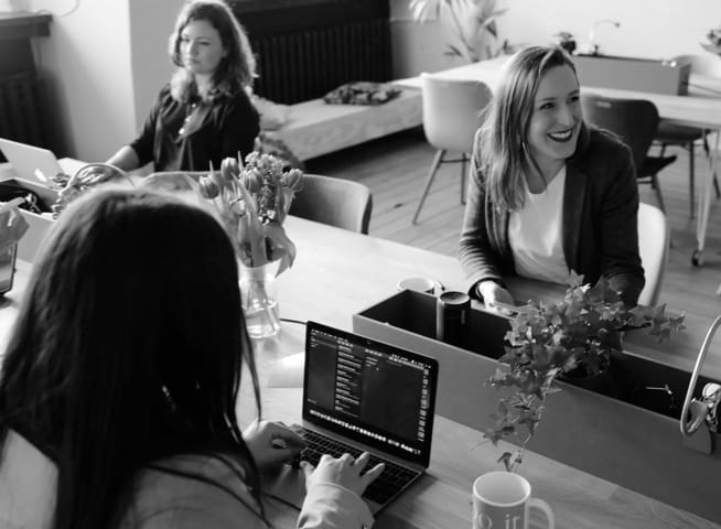 ladies in an office talking smiling and typing a computer